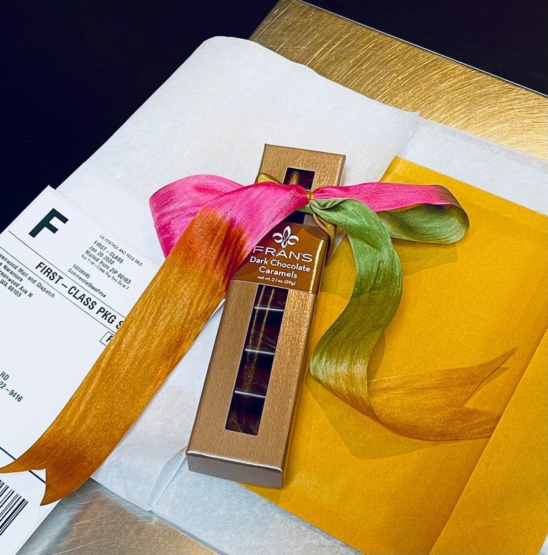 Perfume bottle with pink and green ribbons on white paper and a yellow envelope