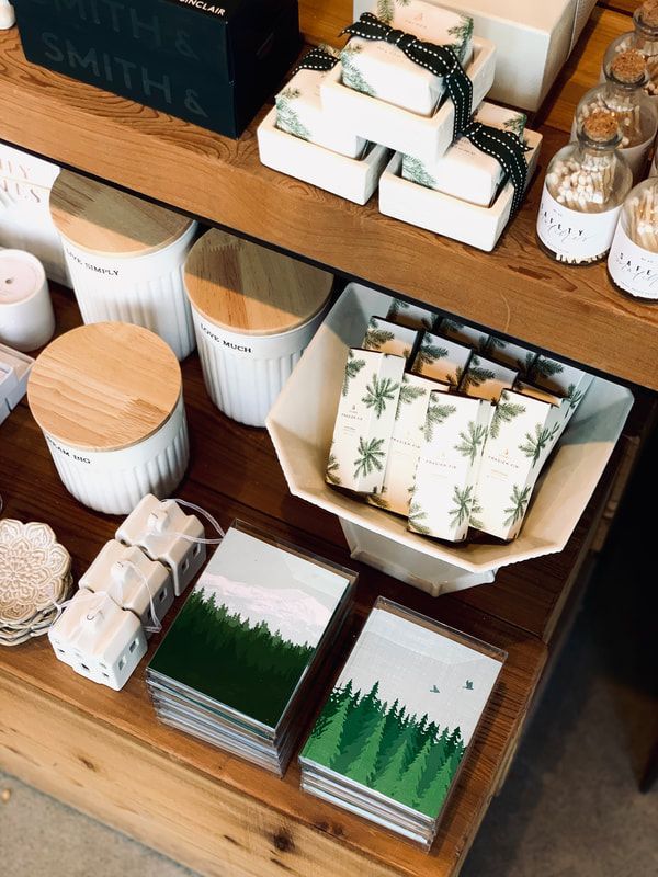 Wooden shelf with packaged candles, small wrapped gifts, and floral stationery in a rustic shop display