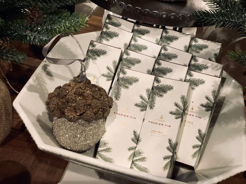 Gift-wrapped white boxes with pine sprigs tied by a chain on a holiday table