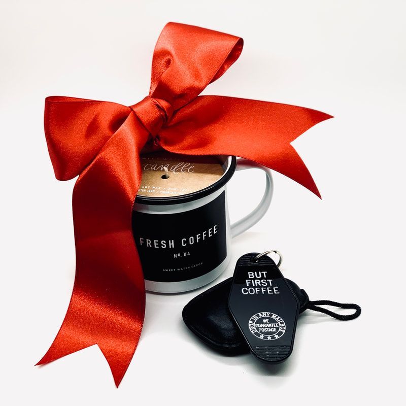Coffee mug gift set with a red satin bow and two black coffee pods on a white background