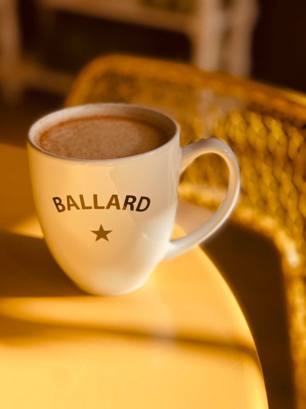 White BALLARD mug on a sunlit table with a blurred yellow chair in the background