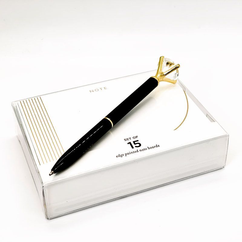 Black-and-gold pen on a white boxed planner or notebook with “2025” on the cover