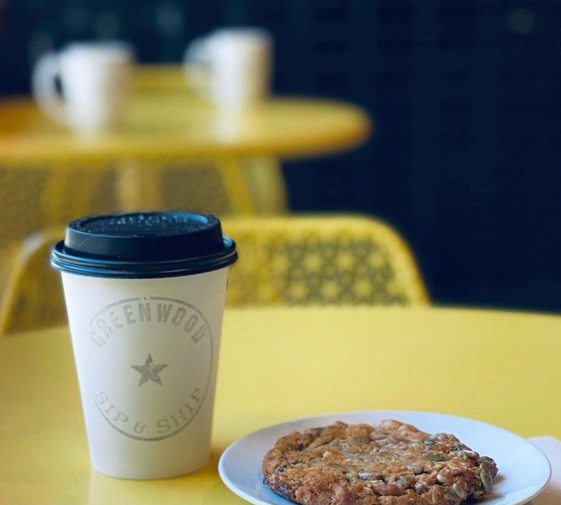 Coffee cup and pastry on a yellow cafe table with blurred chairs in the background