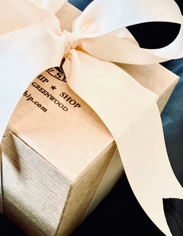 Cream gift box with white ribbon bow on a dark surface