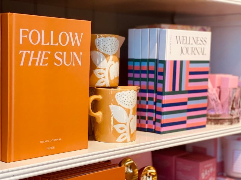 Bright orange “Follow the Sun” book and striped wellness journals on a store shelf