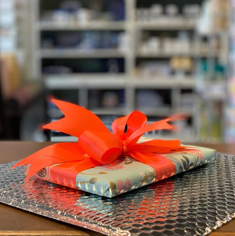 Gift wrapped in red ribbon on a metallic surface with blurred store shelves in the background