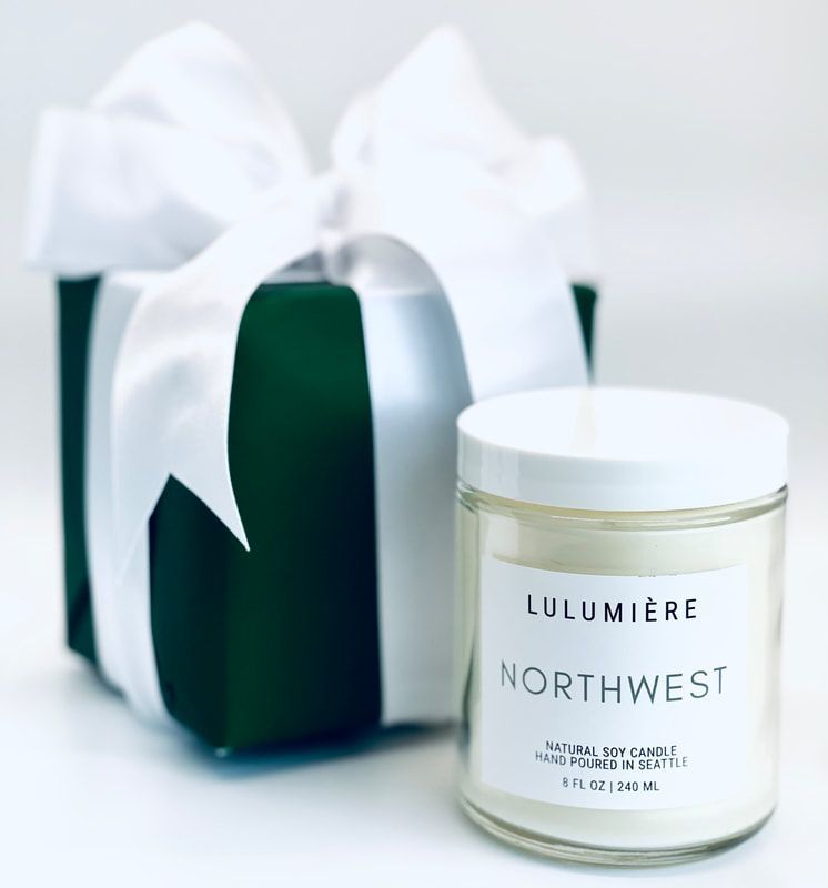 White gift box with bow beside a white candle jar labeled “LULUMIÈRE NORTHWEST.”