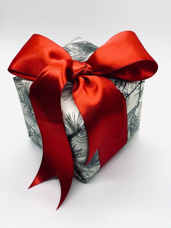 Wrapped gift box with a large red satin bow and silver patterned wrapping paper