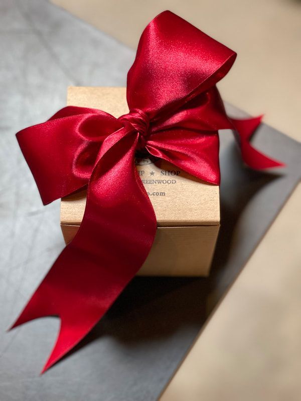 Small gift box wrapped with a red satin ribbon on a gray surface