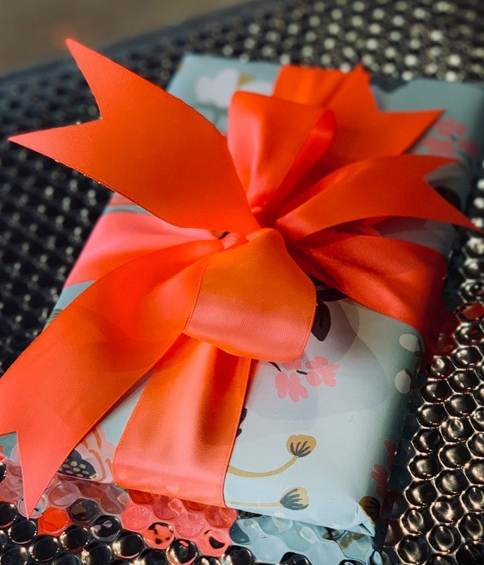 Gift box wrapped in floral paper with a bright orange ribbon bow on top