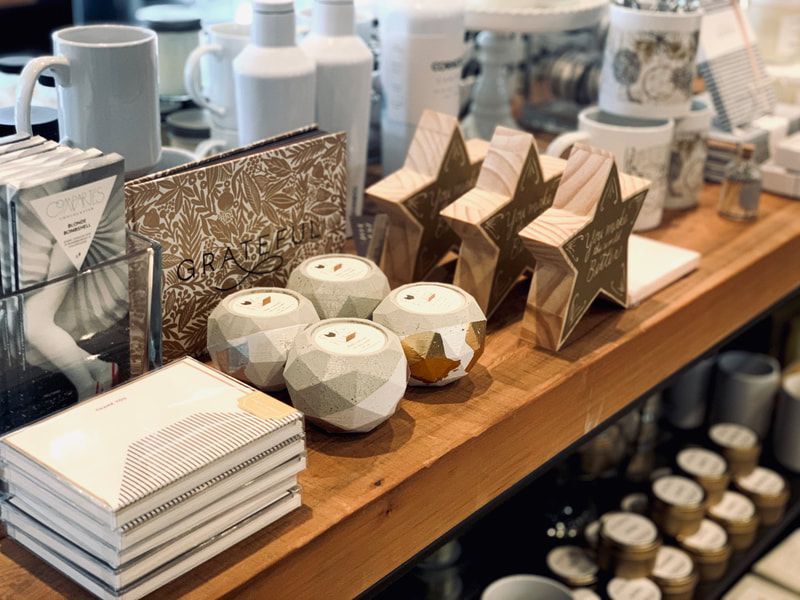 Assorted geometric paper decor and stacked cards displayed on a wooden shelf in a shop