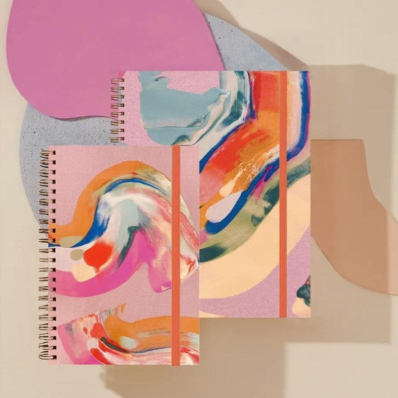Abstract pastel collage with spiral notebooks and layered colorful paint swirls on a beige background