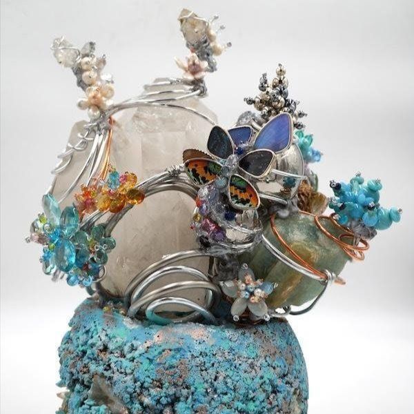 Decorative butterfly figurine with silver wire, clear glass, and blue crystal accents on a textured blue base