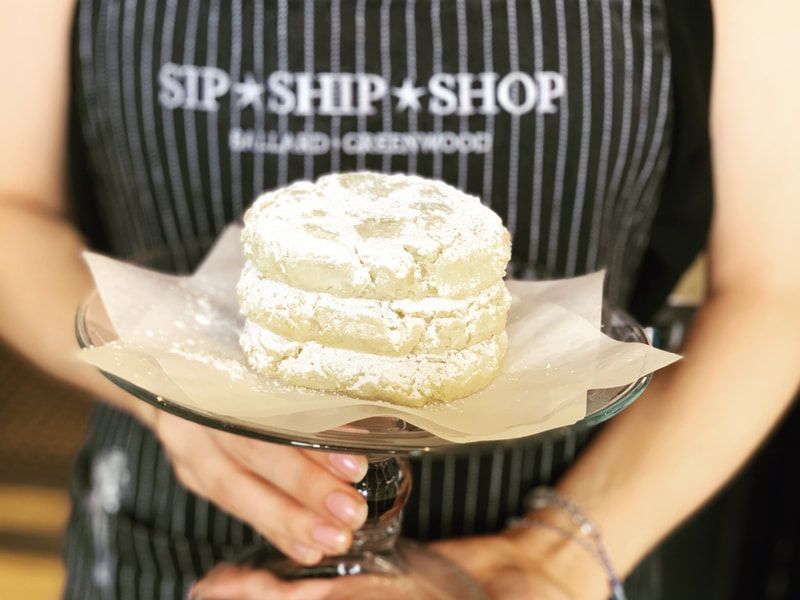 Powdered cake on a glass plate, held by a person in a striped apron