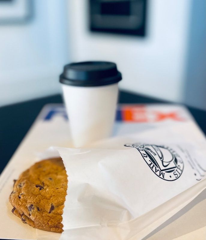 Coffee cup and chocolate chip cookie on a table in a takeaway sleeve