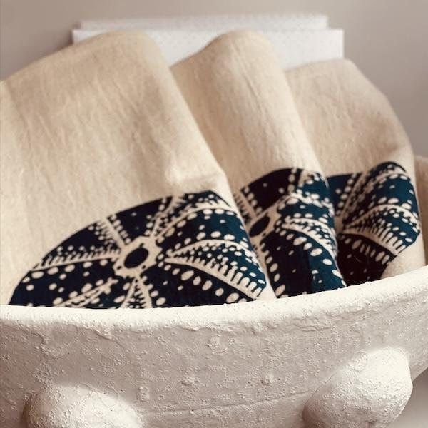 Folded beige and navy patterned towels in a textured white basket