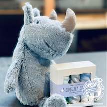 Plush gray unicorn beside a white-and-purple box on a table