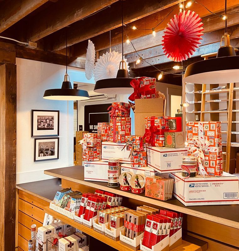 Gift shop display with stacked red-and-white boxes, mugs, and hanging paper decorations on wooden shelves
