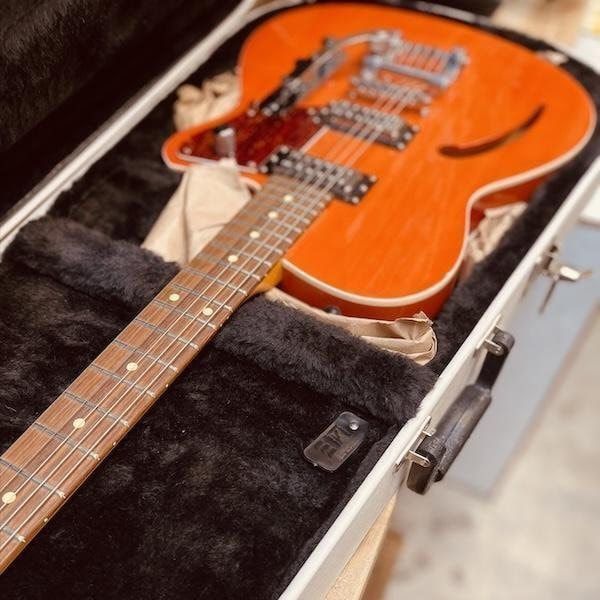 Orange electric guitar in an open black hard case