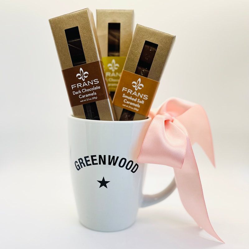 White mug labeled GREENWOOD holds Fran’s Chocolates bars, tied with a pink ribbon.