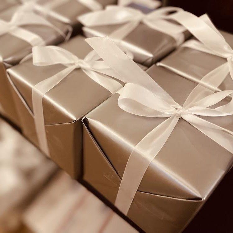 Stacked gold gift boxes with white satin ribbons and bows