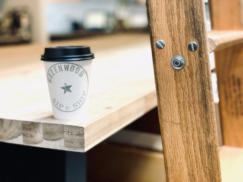 White takeaway cup on a wooden table beside a wooden chair