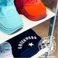 Colorful folded baseball caps on a store shelf, including teal, orange, gray, and black styles.