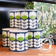 Stacked blue-and-white mugs with green oval patterns on a shelf, with floral wallpaper behind them