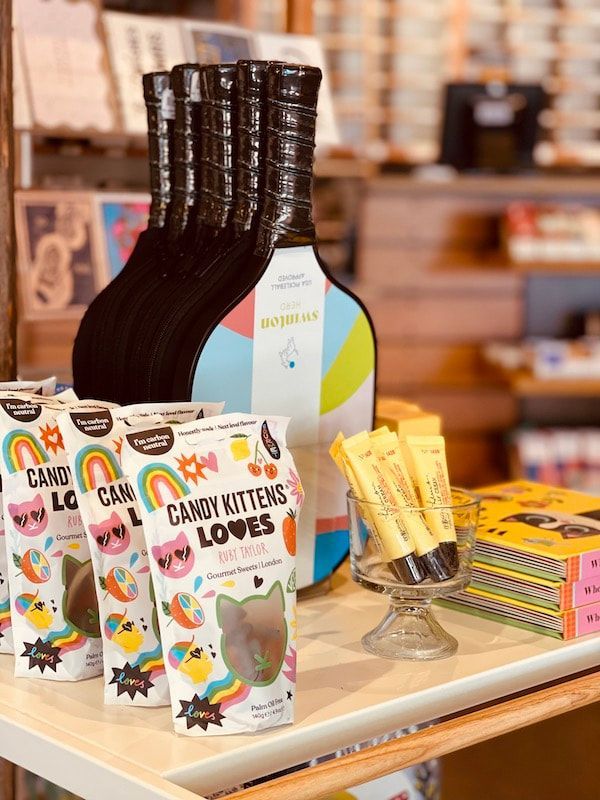 Candy-filled gift display with bottles and colorful cereal boxes on a table in a store.