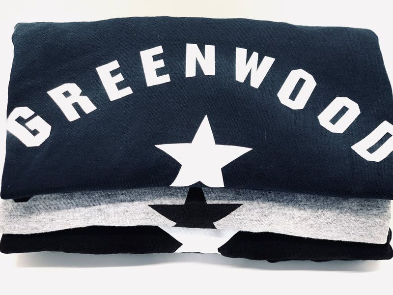 Folded black Greenwood shirt with white lettering and a star emblem