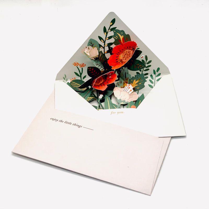 White pop-up greeting card with red, white, and green flowers inside an envelope