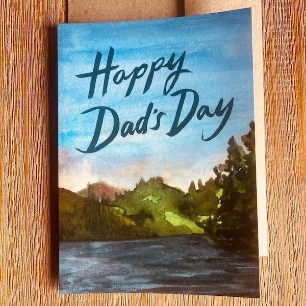 Handmade “Happy Dad’s Day” card with blue sky, lake, and trees in the background