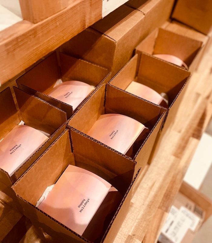 Open wooden drawer with rows of small pink packages in cardboard compartments
