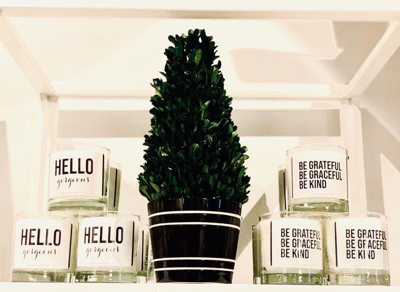 Potted evergreen on a shelf with white and gold “hello” and “be grateful” decor blocks and candles