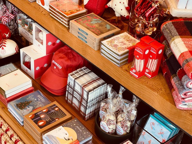 Assorted holiday gift boxes, mugs, and red decorations arranged on a store display shelf.