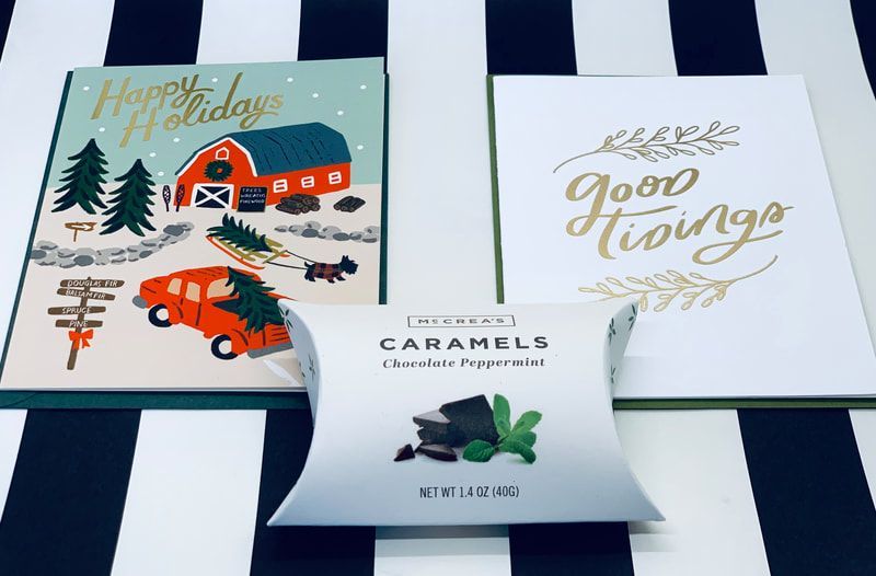 Holiday cards and a caramel box on a blue-and-white striped surface