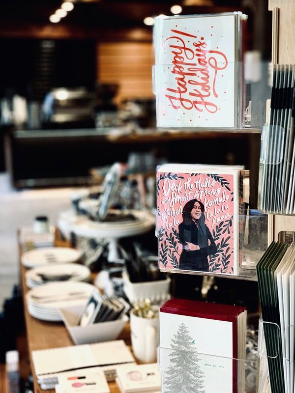 Holiday greeting cards displayed on a cafe counter with a blurred coffee shop background
