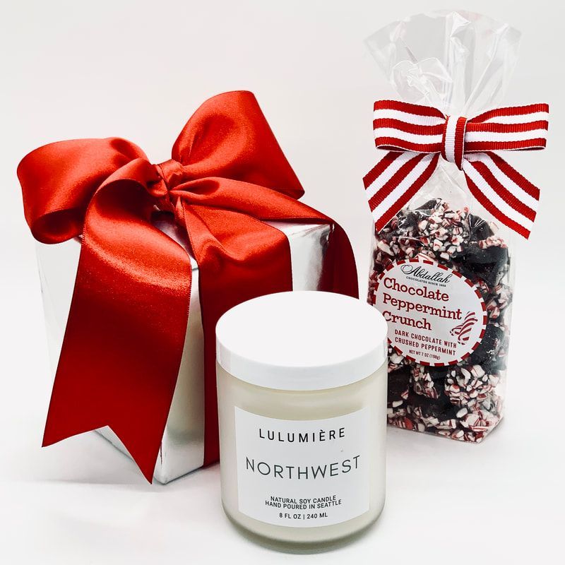 Gift box with red ribbon, white Lumieris Northwest candle, and peppermint chocolate bag on a white background