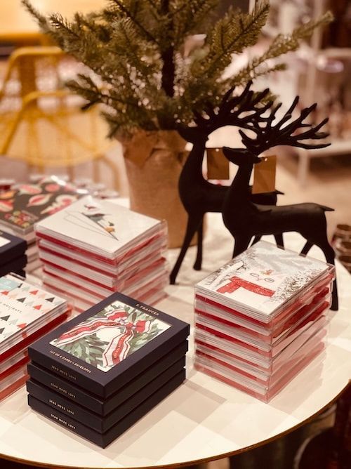 Holiday gift display with stacked red-and-white boxes and black reindeer ornaments on a round table