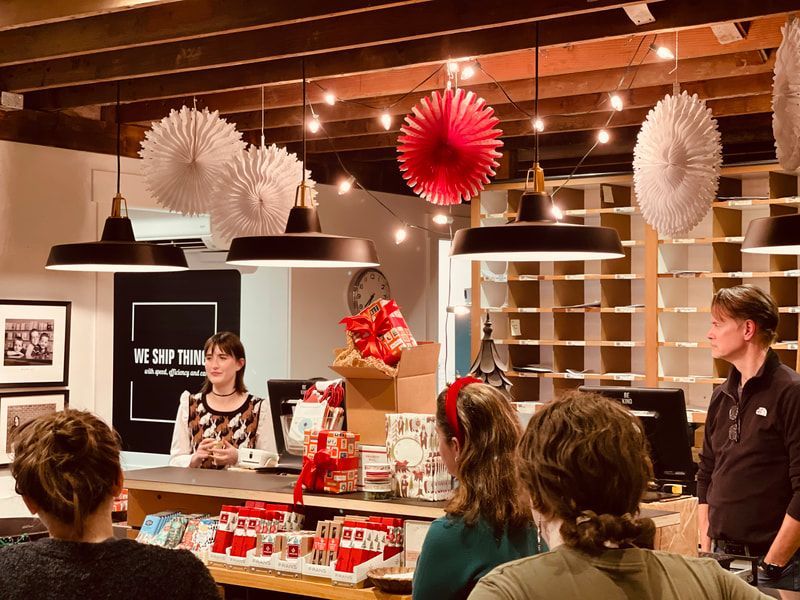 People at a coffee shop counter with red and white hanging decor and pendant lights