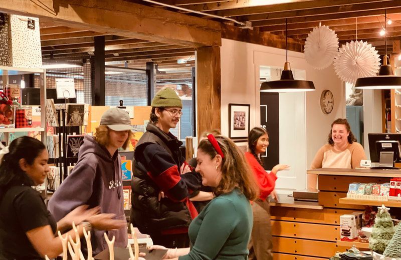 People shopping in a warmly lit store, browsing wooden shelves and decorations.