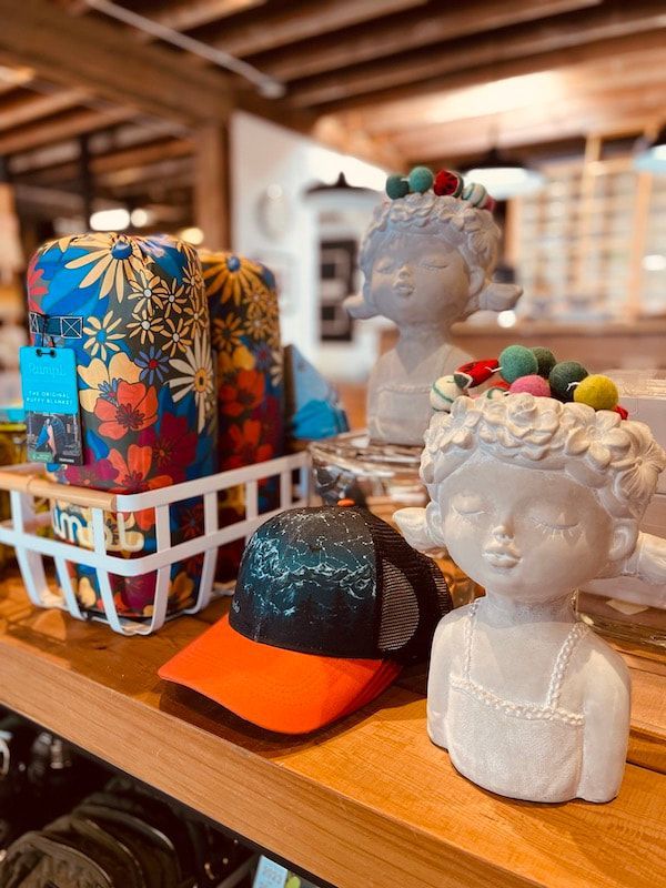 Decorative white busts and colorful candles on a wooden shelf in a shop