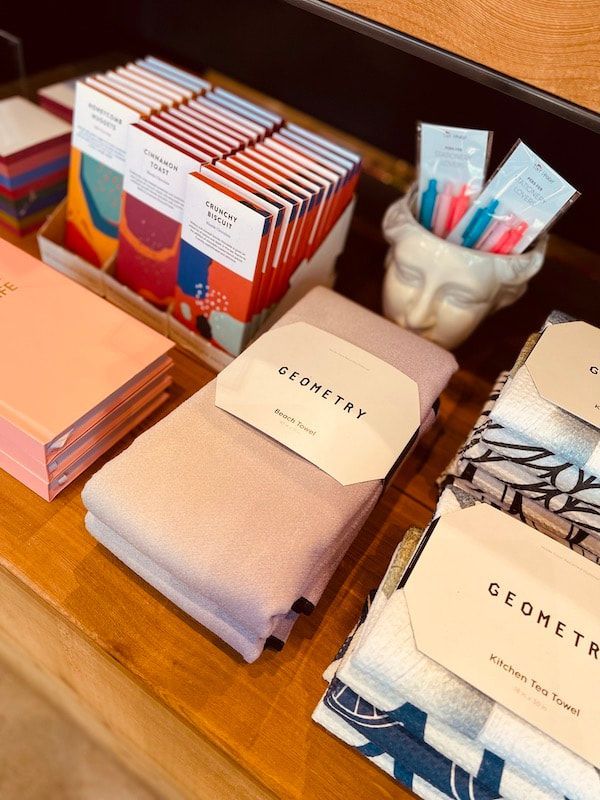 Stacks of illustrated books on a wooden table beside a white bust holding colorful pens and markers.