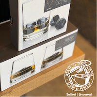 Stacked boxed wine displays on a wooden shelf next to a store logo sign.