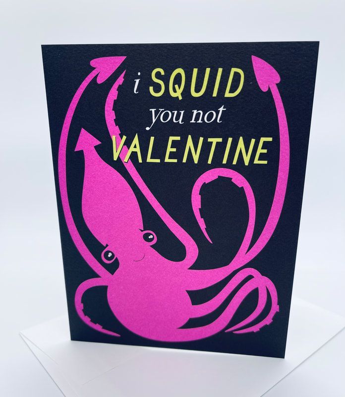 Black card with pink squid and pun “i SQUID you not VALENTINE” on a white surface.