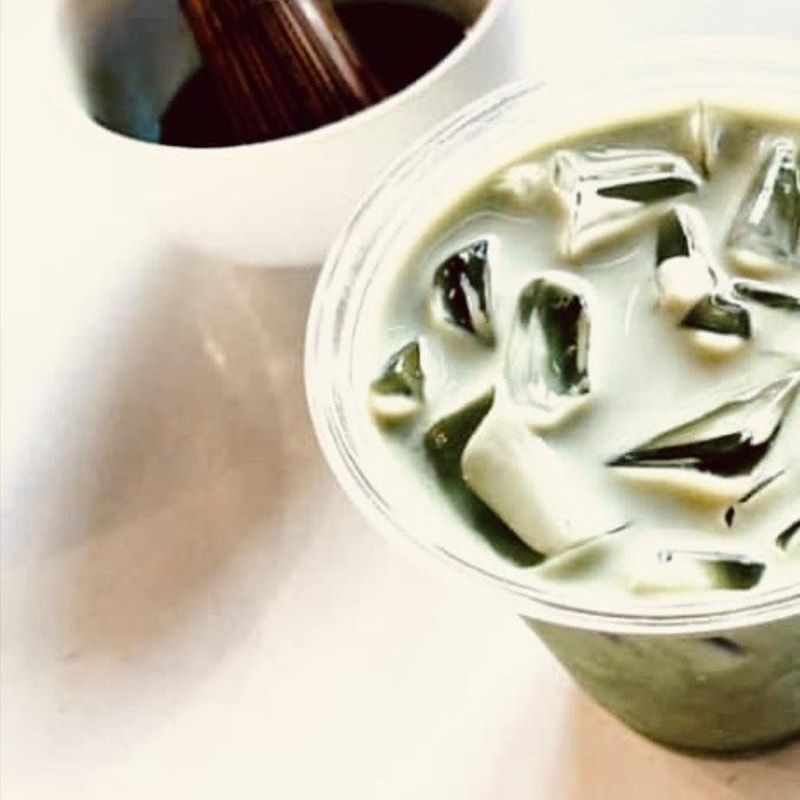 Iced green beverage in a plastic cup beside a bowl of chocolate sauce