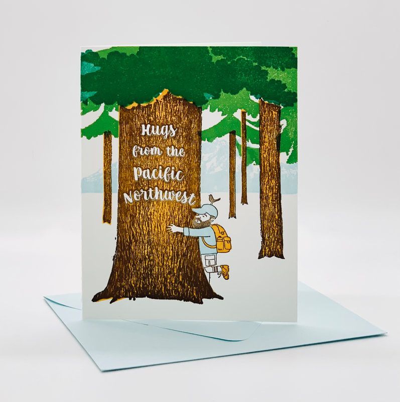 Pop-up card with a forest scene and a person hugging a tree, reading “Hugs can be a pacific Northwest.”