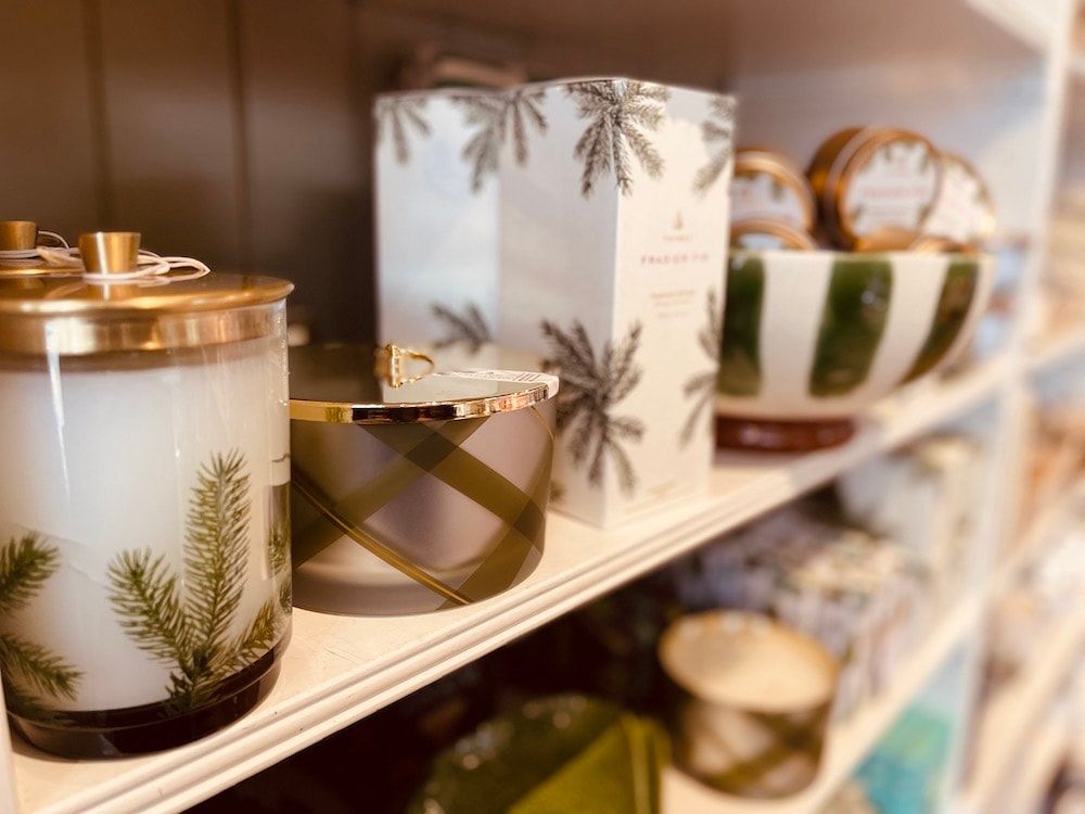 Holiday candles and decorative mugs with gold accents on a store shelf