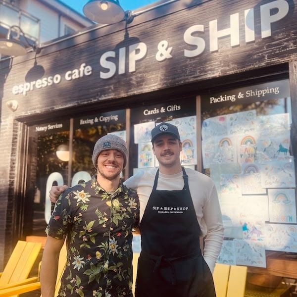 Two smiling staff outside SIP & SHIP espresso cafe, wearing aprons in front of the storefront.