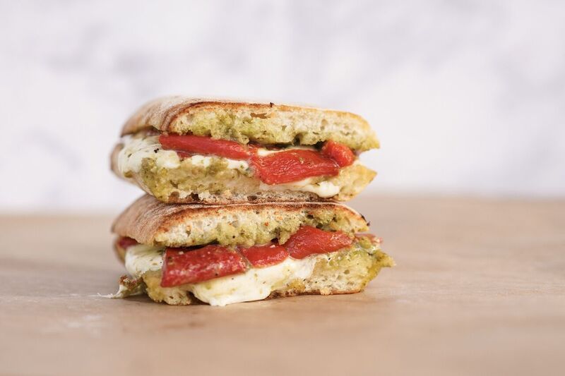 Stacked sandwich halves with strawberry filling on a wooden surface